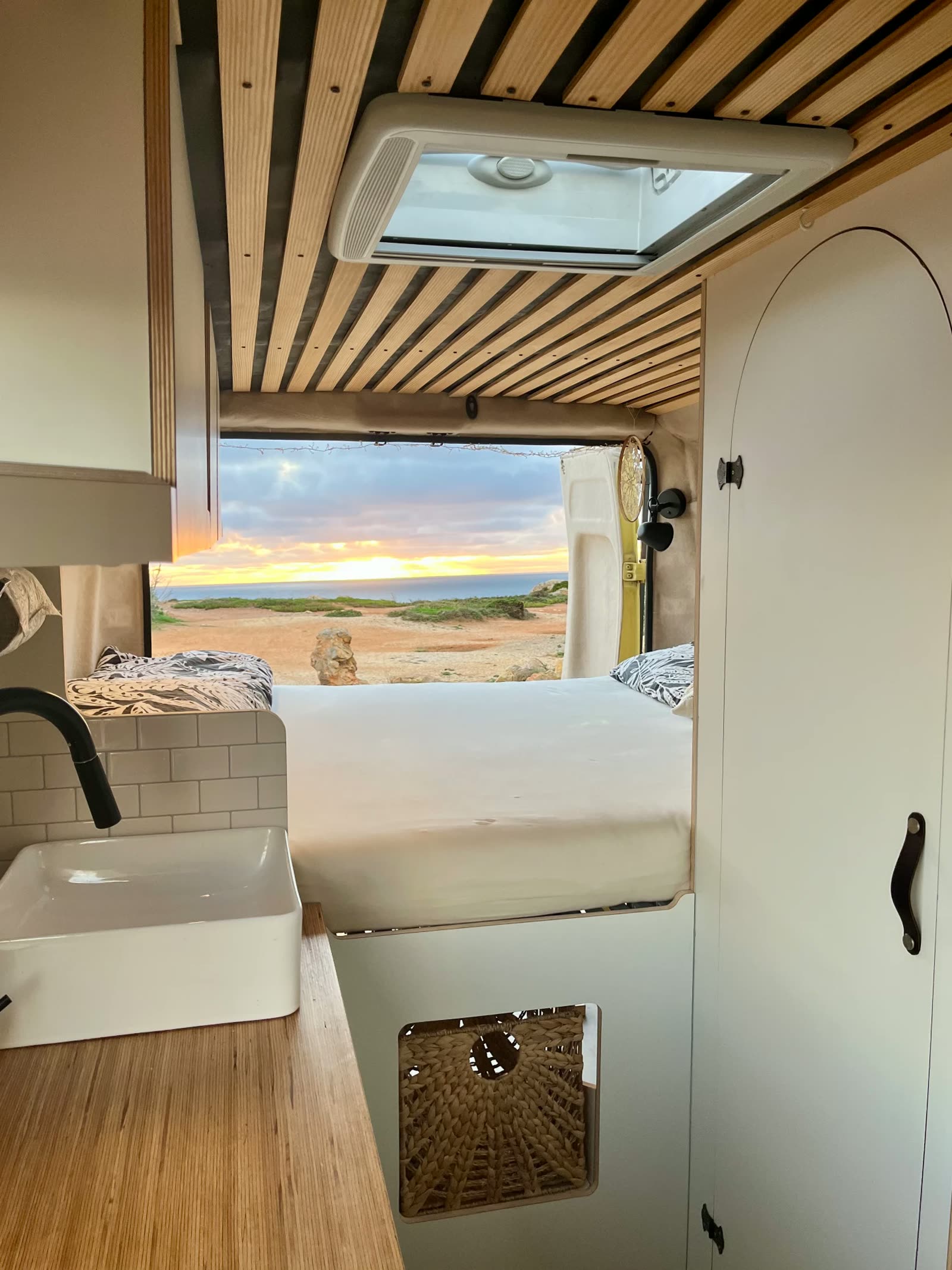 Camper-Innenraum mit Bett und Meerblick